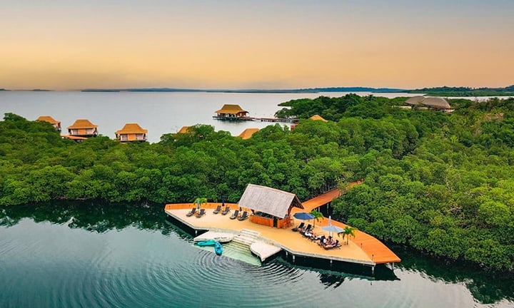 Guests on the sand at Kupu Kupu Beach with the Tipsy Bar at Nayara Bocas del Toro